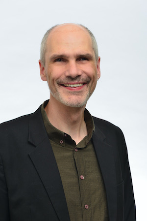Reiner Delgado, lächelnd mit Anzug