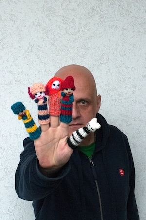 Der Künstler hält auf jedem Finger eine kleine Fingerpuppe.
