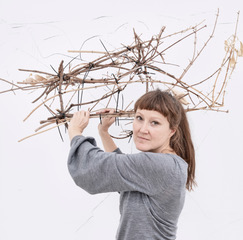 Stella Geppert hält vor einer weißen Wand dornig wirkende Holzbündel