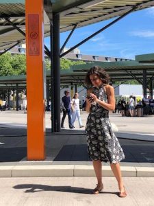 Stella Luncke mit einem Handy in der Hand am Busbahnhof stehend.